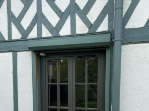 Fenêtre double anthracite, coffre volet roulant assorti sur façade colombages vert