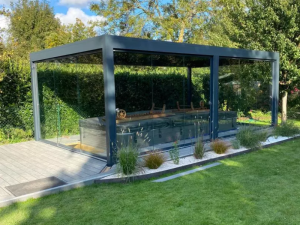 Pool-house vitré anthracite abritant spa couvert, pelouse et haie verte