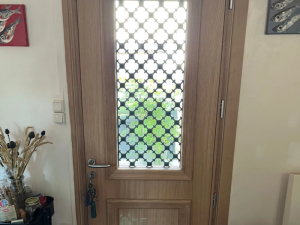 Porte bois clair intérieur, vitrail avec grille métal noire à motifs géométriques