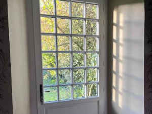 Porte blanche petits bois 24 carreaux, ombre croisillons sur mur intérieur