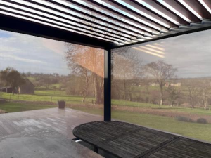 Sous pergola bioclimatique, lames sombres et stores latéraux sur campagne