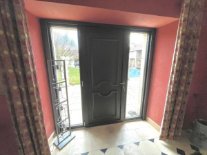 Porte anthracite moulurée avec tierces vitrées, hall terracotta et carrelage clair