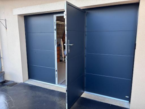 Porte garage sectionnelle anthracite, portillon ouvert sur parpaings intérieurs