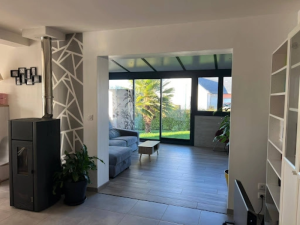 Salon carrelé ouvrant sur extension baies noires, palmier visible dans le jardin