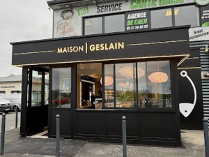 Devanture noire Maison Geslain, lettrage dore et luminaires en osier