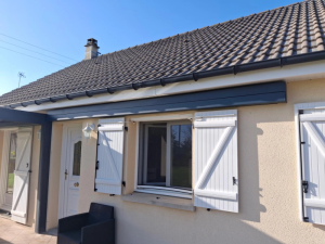 Coffre store banne anthracite au-dessus menuiseries blanches facade beige