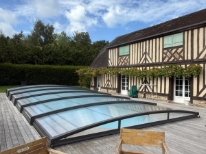 Abri piscine bas telescopique anthracite sur terrasse bois, maison à colombages