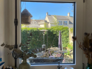 Fenêtre blanche intérieure, vases et vue jardin sur maisons colombages