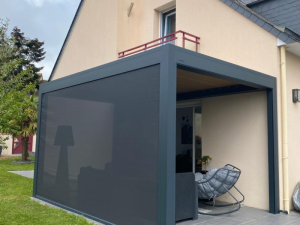Pergola anthracite, store zip latéral déployé et fauteuil basculant gris