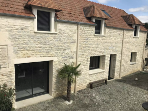 Longère pierre rénovée, menuiseries noires, lucarnes volets gris et cour gravier palmier