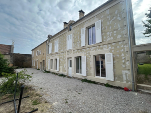 Longère pierre en rénovation, volets battants blancs persiennés sur la façade