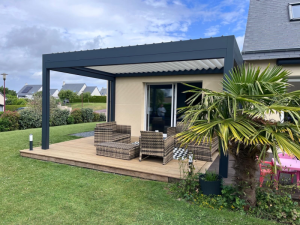 Pergola bioclimatique grise sur terrasse bois, salon résine marron et palmier