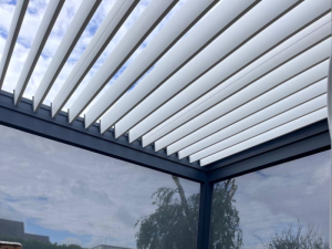 Coin pergola, lames blanches entrouvertes et screens gris sur deux côtés