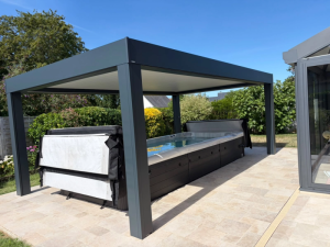 Pergola grise bioclimatique au-dessus d'un spa de nage gris sur terrasse travertin