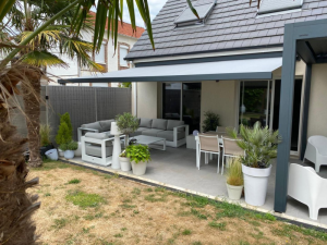 Store banne gris clair déployé, salon L blanc et palmiers sur grande terrasse