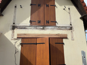 Volets aspect chêne et pentures noires, traces de cadre ancien sur crépi rénové
