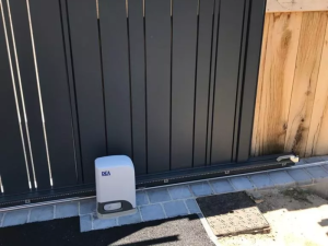 Moteur DEA au pied d'un portail coulissant lames anthracite sur pavés gris