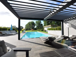 Pergola bioclimatique grise, ombres en bandes sur terrasse carrelee et piscine