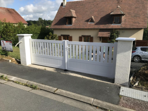 Portail battant blanc deux vantaux ajourés entre piliers crépi, allée goudron