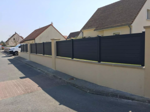Cloture anthracite lames horizontales pleines sur muret beige le long de rue