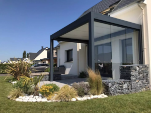 Pergola anthracite paroi vitree, jardin paysager cailloux blancs et gabions