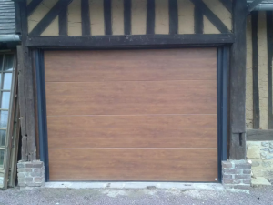 Porte garage sectionnelle aspect chene dans facade colombages sombres