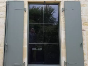 Fenetre anthracite petits bois, volets vert sauge ouverts sur mur pierre