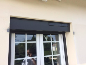 Coffre volet roulant anthracite avec panneau solaire au-dessus fenetre blanche