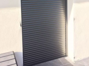 Volet roulant anthracite entierement baisse sur facade creme et carrelage