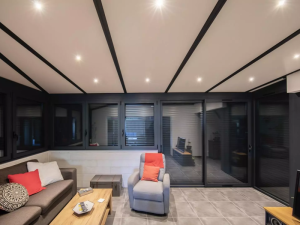 Interieur veranda, plafond poutres noires, volets gris et coin canape