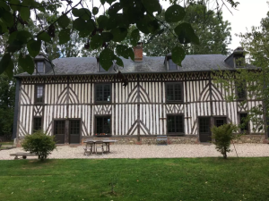 Longère colombages, menuiseries brun foncé, lucarnes et table jardin sur gravier