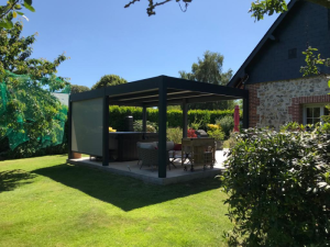 Pergola anthracite store zip, spa et salon rotin sur dalle devant maison pierre