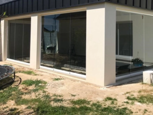 Parois vitrees coulissantes entre piliers beige, toiture anthracite