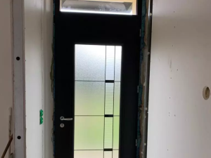 Porte noire vitrage dépoli rayures, pose sur chantier avec mousse isolation bleue