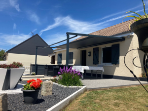 Store banne gris anthracite deploye, table blanche et jardin fleuri