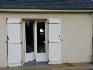 Porte-fenêtre blanche 2 vantaux, volets battants barres et écharpes, terrasse bois