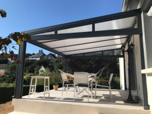 Pergola alu anthracite toit polycarbonate, salon blanc sur terrasse carrelée