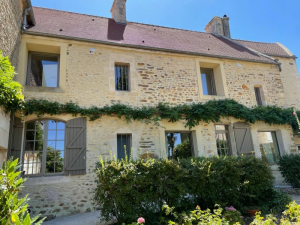 Maison pierre deux étages, fenêtres gris taupe et volets assortis sous ciel bleu