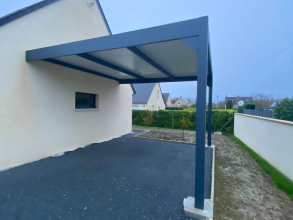 Carport alu anthracite adossé, toit panneaux clairs, enrobé noir, façade beige