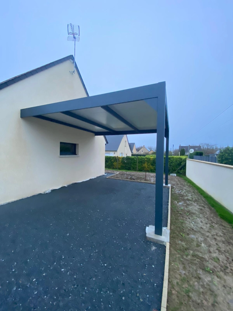 Carport alu anthracite adossé, toit panneaux clairs, enrobé noir, façade beige