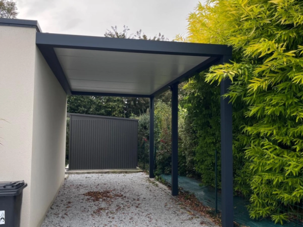 Carport alu anthracite adossé toit blanc, allée gravier et haie bambous