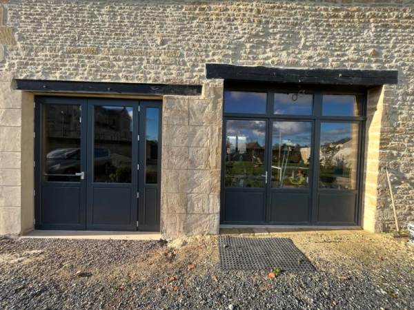 Portes alu anthracite vitrées sur mur pierre, gravier devant, linteau bois