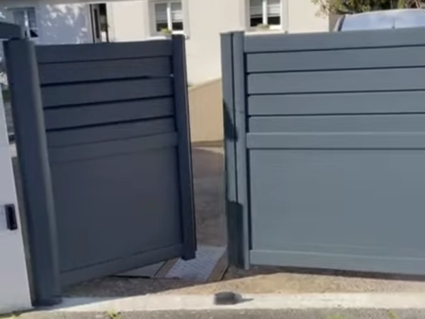 Portail battant alu anthracite mi-clair à lames, un vantail ouvert sur allée béton