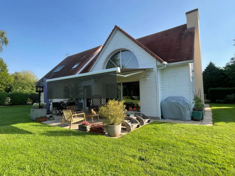 Store banne anthracite, lambrequin déroulé, bardage blanc, terrasse pierre