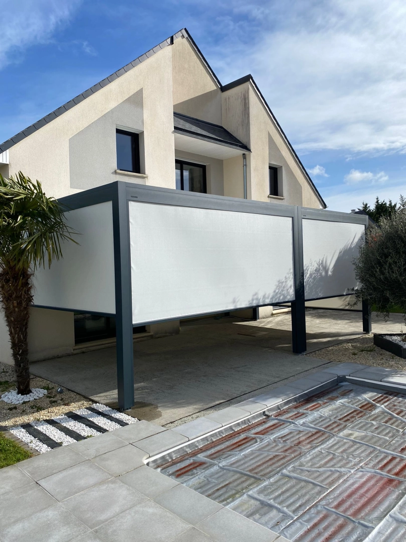 Pergola anthracite avec stores verticaux blancs sur terrasse béton, piscine au premier plan