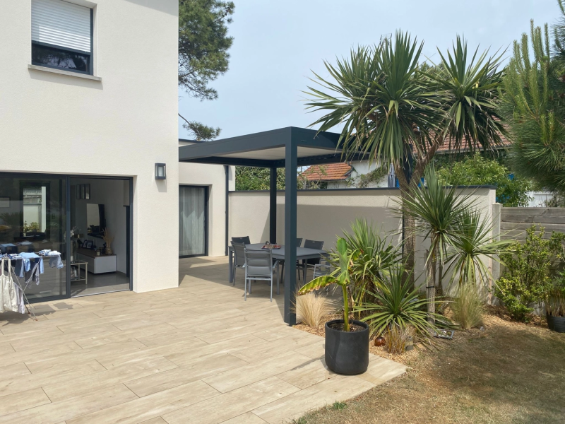 Pergola anthracite toit plat, terrasse carrelage aspect bois et table grise