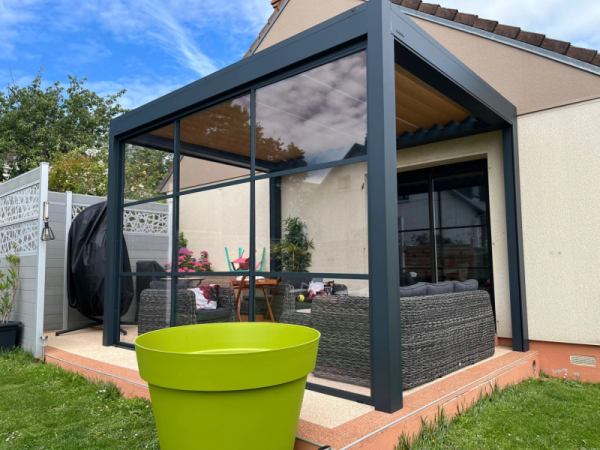 Pergola bioclimatique anthracite parois vitrées, terrasse béton désactivé bordée