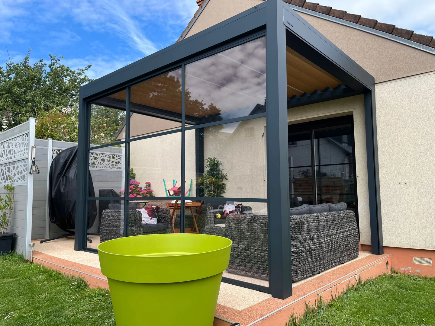 Pergola bioclimatique anthracite parois vitrées, terrasse béton désactivé bordée