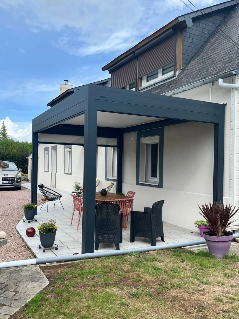 Pergola bioclimatique anthracite, store blanc, terrasse grise et table ronde bois