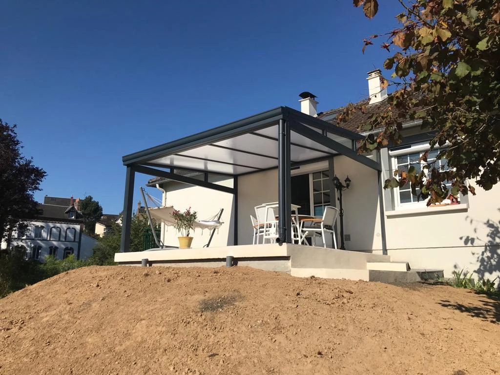 Pergola alu anthracite toit polycarbonate blanc, terrasse béton, terre végétale devant